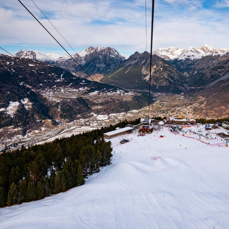 Fotografie einer Skipiste in Bormio in Italien samt Seilbahn und Bergen am Horizont