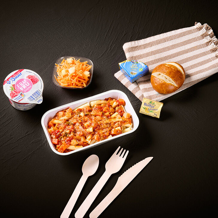 Pasta in tomato sauce in an aluminium bowl, potato salad in a plastic cup, bread rolls, packaged butter and cheese